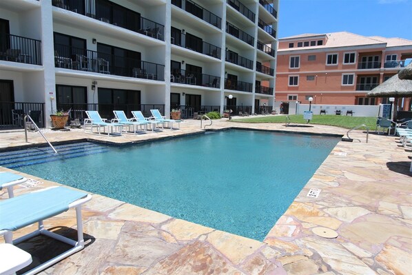 A swimming pool with lounge chairs and a stone deck.
