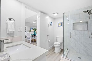 Un baño moderno con un lavabo grande, inodoro y ducha con mampara de vidrio.
