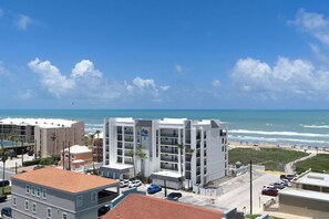 Un hotel costero con varios pisos, un estacionamiento y vista a la playa y al océano.