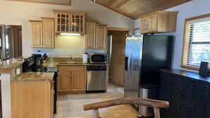 Una cocina con armarios de madera, electrodomésticos de acero inoxidable y un banco de madera.