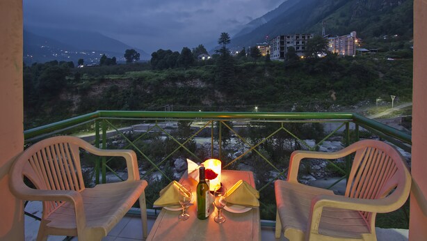 A balcony with two chairs, a table, a bottle, and two glasses. - Royal Park Resort (Manali)