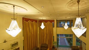 A hotel lobby with chandeliers, patterned sofas, a travel desk, and a view of the outside. - Royal Park Resort (Manali)