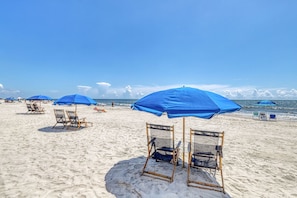 Relax on the beach with comfortable chairs under shaded umbrellas.