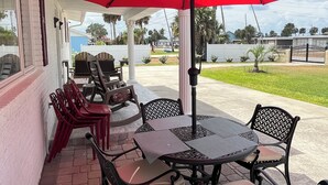 An outdoor patio with a red umbrella, black metal chairs, and a table. - Beautiful vacation home - just 2-Minute Walk to World-Famous Daytona Beach (Daytona Beach)