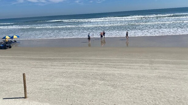 A beach with people walking, a sandy shore, and a clear sky. - Beautiful vacation home - just 2-Minute Walk to World-Famous Daytona Beach (Daytona Beach)