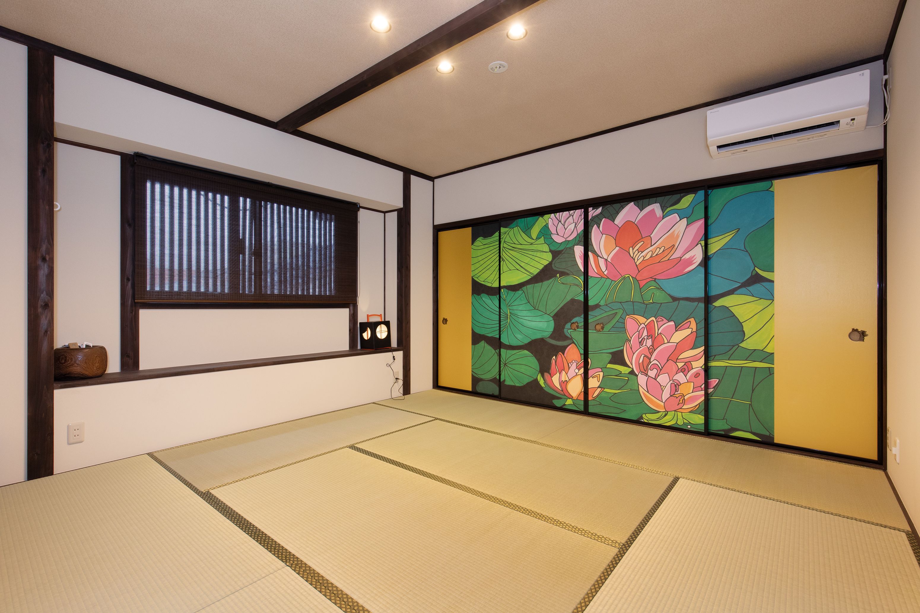 Habitació japonesa tradicional amb sòls de tatami, una porta corredissa amb decoració floral, una finestra amb persianes i un aparell d'aire condicionat.