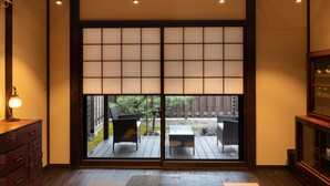 Una habitació japonesa tradicional amb paviment de tatami, portes corredisses shoji, una taula de fusta i una televisió.