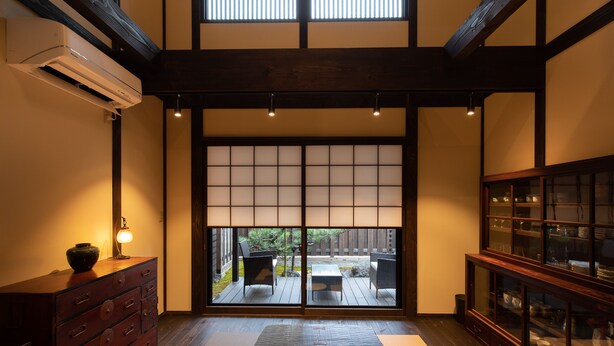 Habitació japonesa tradicional amb sòls de tatami, portes diapòsits shoji, un armari de fusta i vista a un jardí.