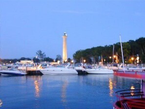 Ein Yachthafen mit vertäuten Booten, im Hintergrund ein markanter Leuchtturm und eine ruhige Abendstimmung.