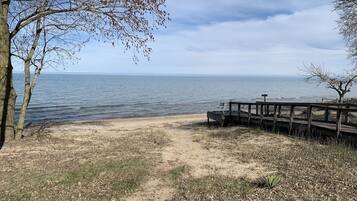 A beach with a wooden pier and a bench.