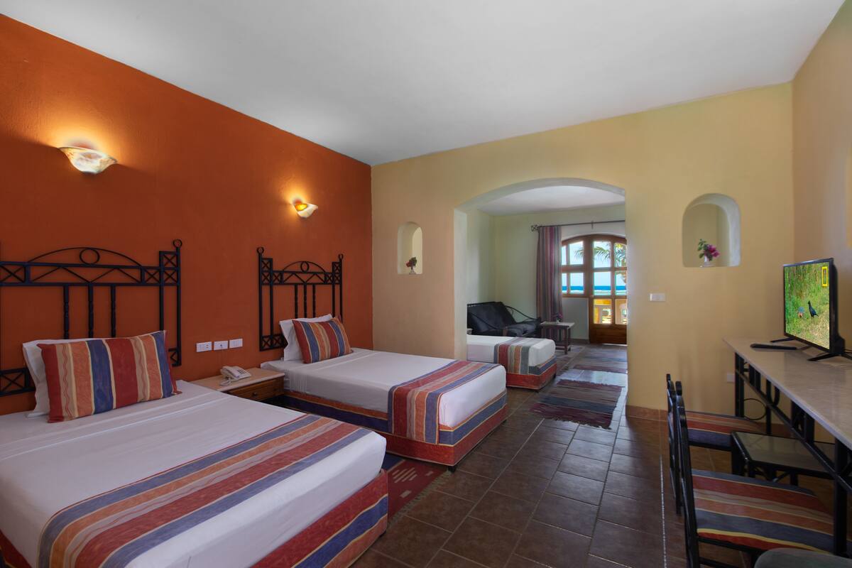 A hotel room with two beds, a desk, and a TV.