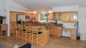 A modern kitchen with wooden cabinets, a central island with bar stools, a built-in microwave, and a large window providing natural light. - Beautiful Tahoe Chalet, 5 BR, 3 Bath, Hot Tub, Jacuzzi Bath, 3 Spacious Decks (South Lake Tahoe)
