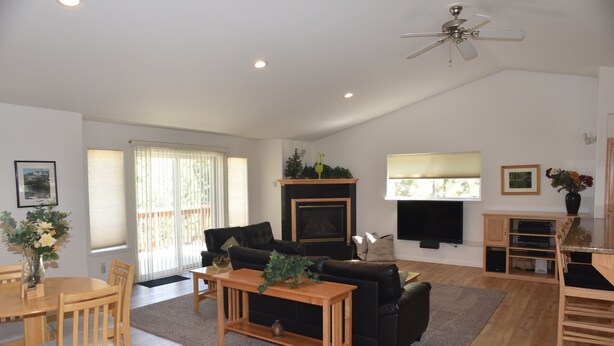 A spacious living room with a fireplace, a dining area, and a TV mounted on the wall. - Beautiful Tahoe Chalet, 5 BR, 3 Bath, Hot Tub, Jacuzzi Bath, 3 Spacious Decks (South Lake Tahoe)
