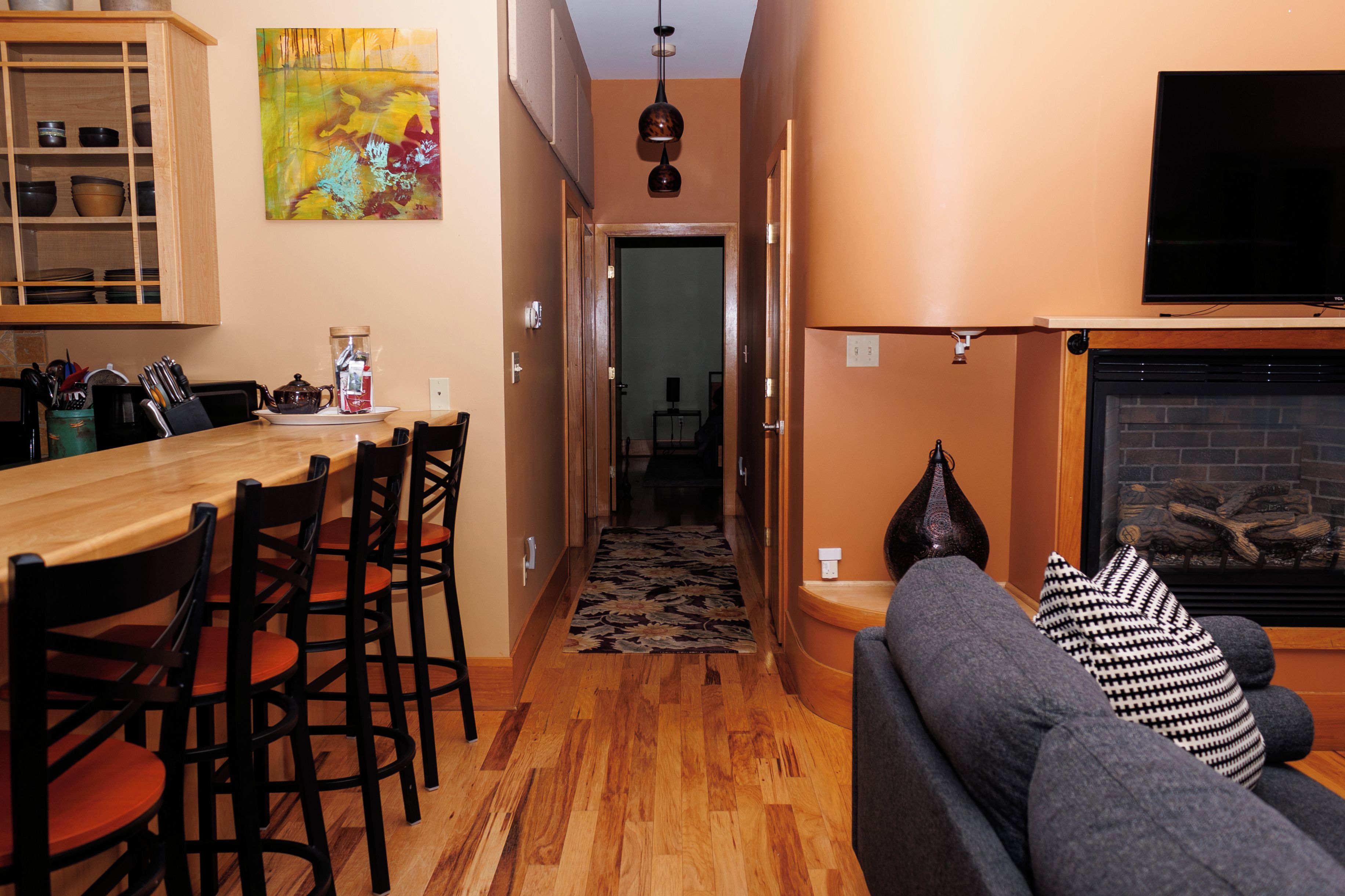 Una sala acogedora con chimenea, un comedor con muebles de madera, y un pasillo que lleva a otra habitación.