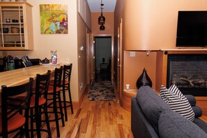 Una sala acogedora con chimenea, un comedor con muebles de madera, y un pasillo que lleva a otra habitación.
