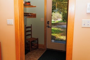 A wooden door with a glass panel, a chair, and a shelf with containers.