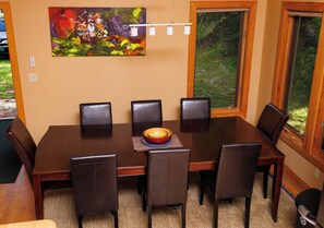 A dining room with a wooden table, six chairs, and a bowl of fruit.