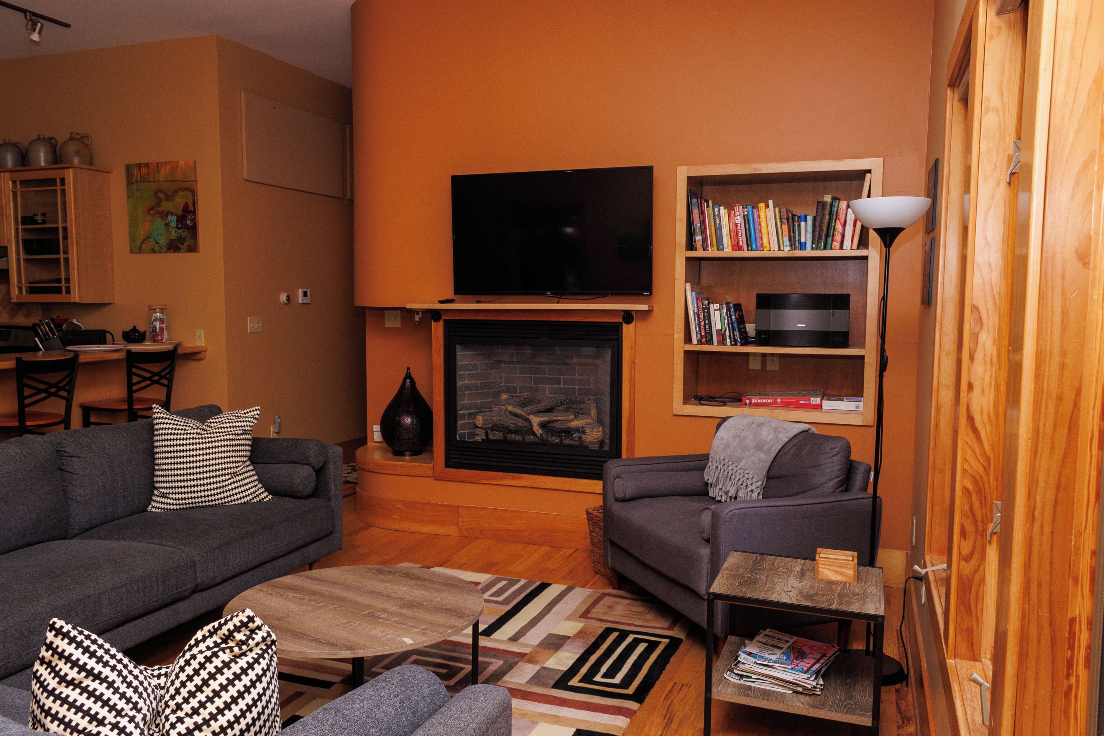 Una sala de estar con chimenea, televisor, estantería y sofá.