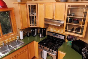 A kitchen with wooden cabinets, a stainless steel stove, and a coffee maker.