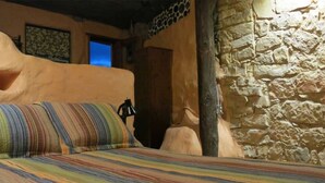 A room with a stone wall, a wooden door, and a bed with a striped blanket.