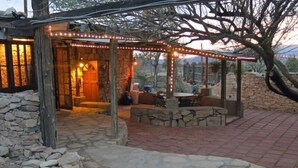 A stone-walled building with a covered patio area featuring outdoor seating and string lights.