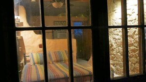 A room with a bed, a window, and a stone wall.