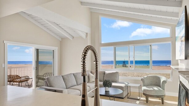 Un salon moderne avec vue sur la plage, une grande fenêtre et un robinet de cuisine au design unique.
