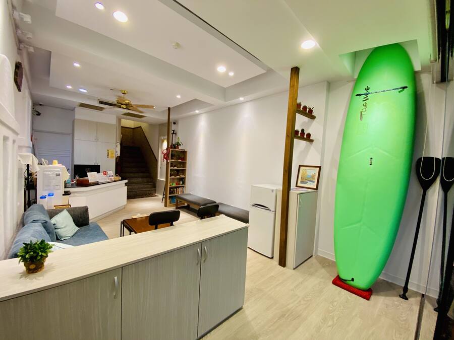 A modern kitchen with a dining area, a staircase, and a surfboard.