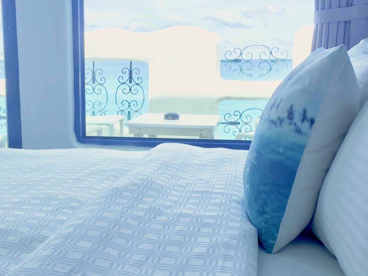 A bedroom with a bed, a window, and a view of a beach.