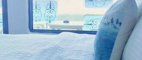 A bedroom with a bed, a window, and a view of a beach.
