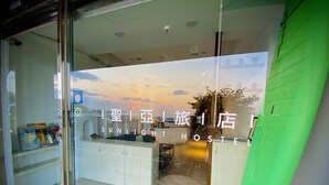 A hotel reception area with a modern design, a reception desk, and a view of the sky through the window. - Seya Inn (Hengchun)