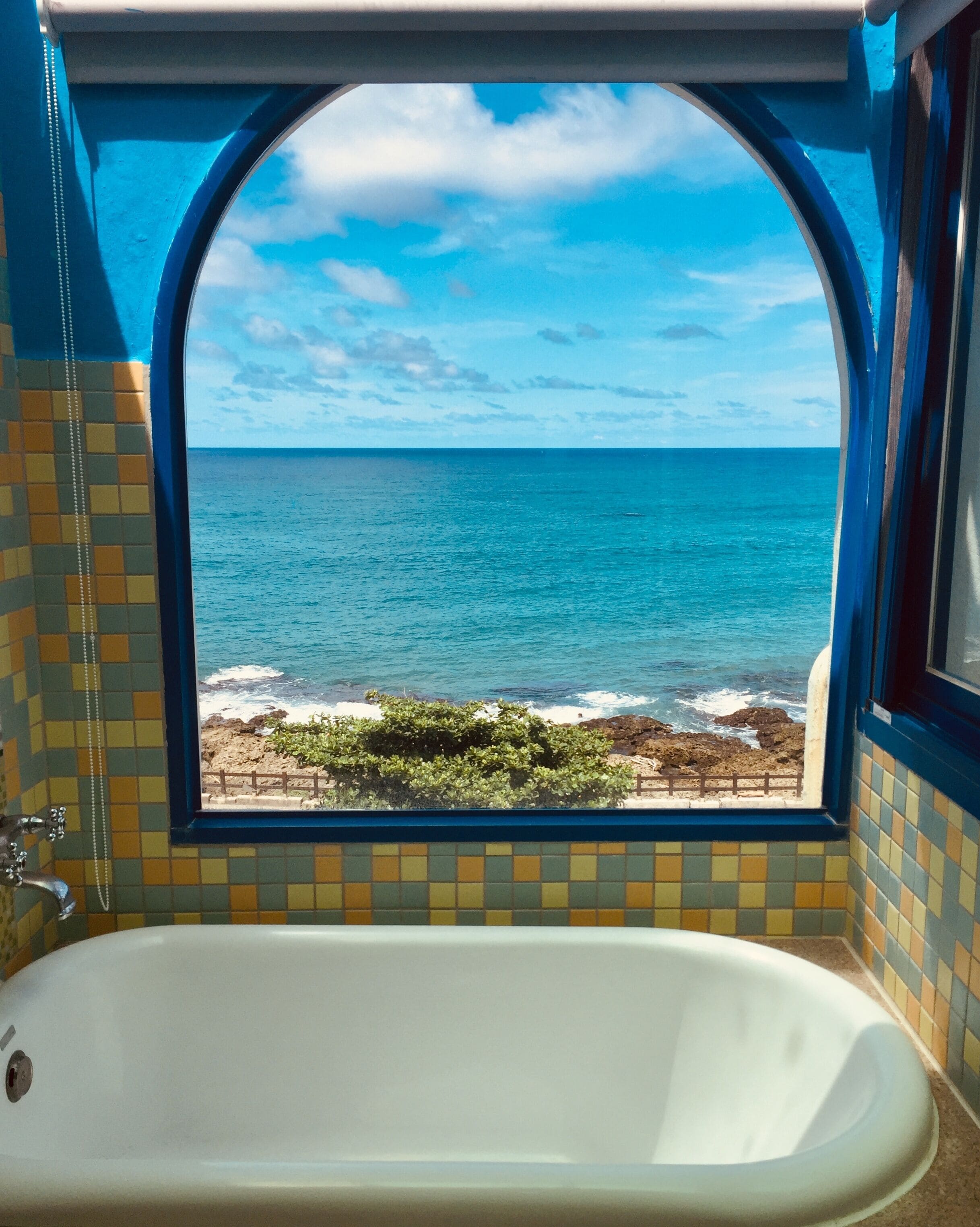 Une baignoire donnant sur l’océan par une fenêtre.