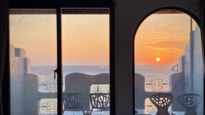 A room with a bed and a view of the sunset over the sea through a window. - Seya Inn (Hengchun)