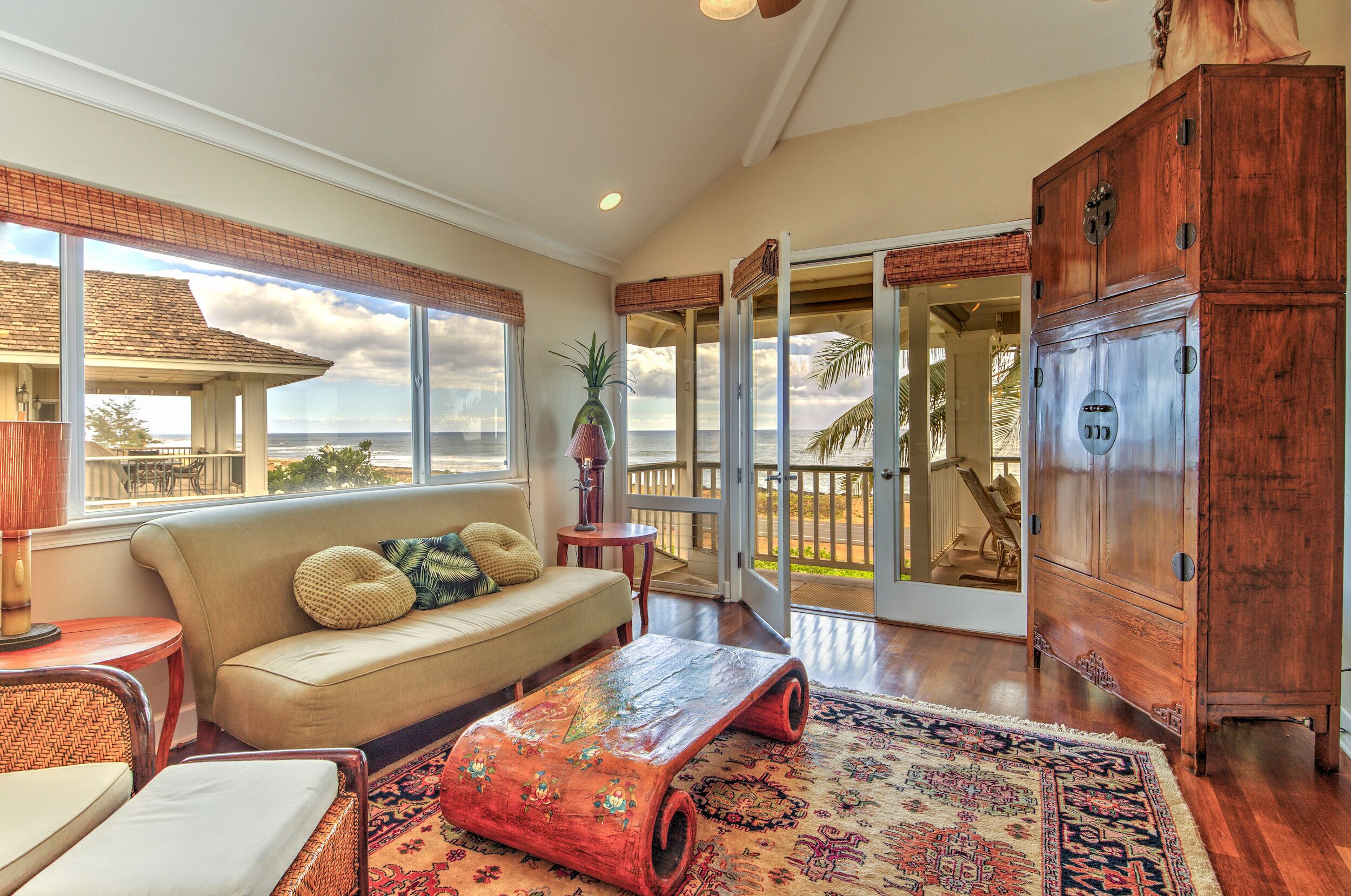 A spacious living room with a large window, a wooden cabinet, and a cozy seating area.