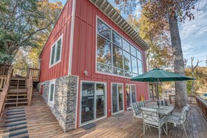 A red two-story house with a deck, stone foundation, and large windows. - Firefly - 2 Houses on 1 Spectacular Property (Belmont)