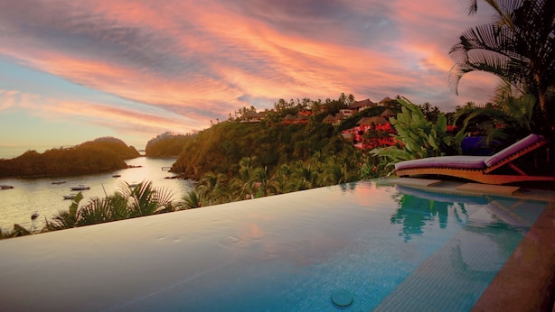 An infinity pool with a view of a coastal landscape and a sunset. - Casita Jazmin Careyes - Beachfront Villa - Infinity Pool - Exoticdigs Collection (Careyes)