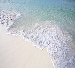 Una playa arenosa con agua cristalina y olas suaves.