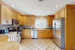 Enjoy cooking in this well-equipped kitchen with a stainless steel refrigerator, microwave, oven, and dishwasher.