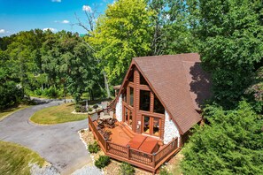 A cabin with a deck, large windows, and a stone exterior.