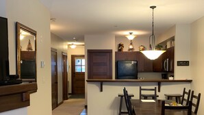 Una cocina moderna con comedor, que incluye una isla central, armarios de madera y un televisor integrado.