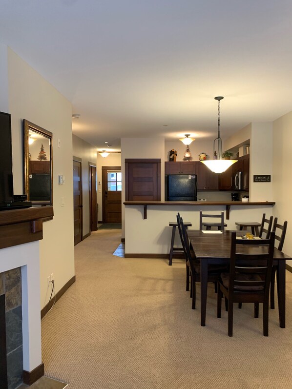 A modern kitchen with a dining area, featuring a central island, wooden cabinets, and a built-in television.