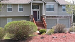 A two-story house with a front porch, stone pillars, and a garage.