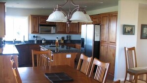 A spacious kitchen with wooden cabinets, a central island, and a dining area with a table and chairs.