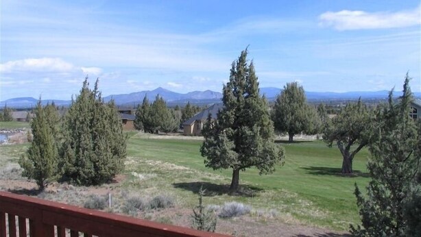 A residential area with houses, trees, and a mountainous backdrop.