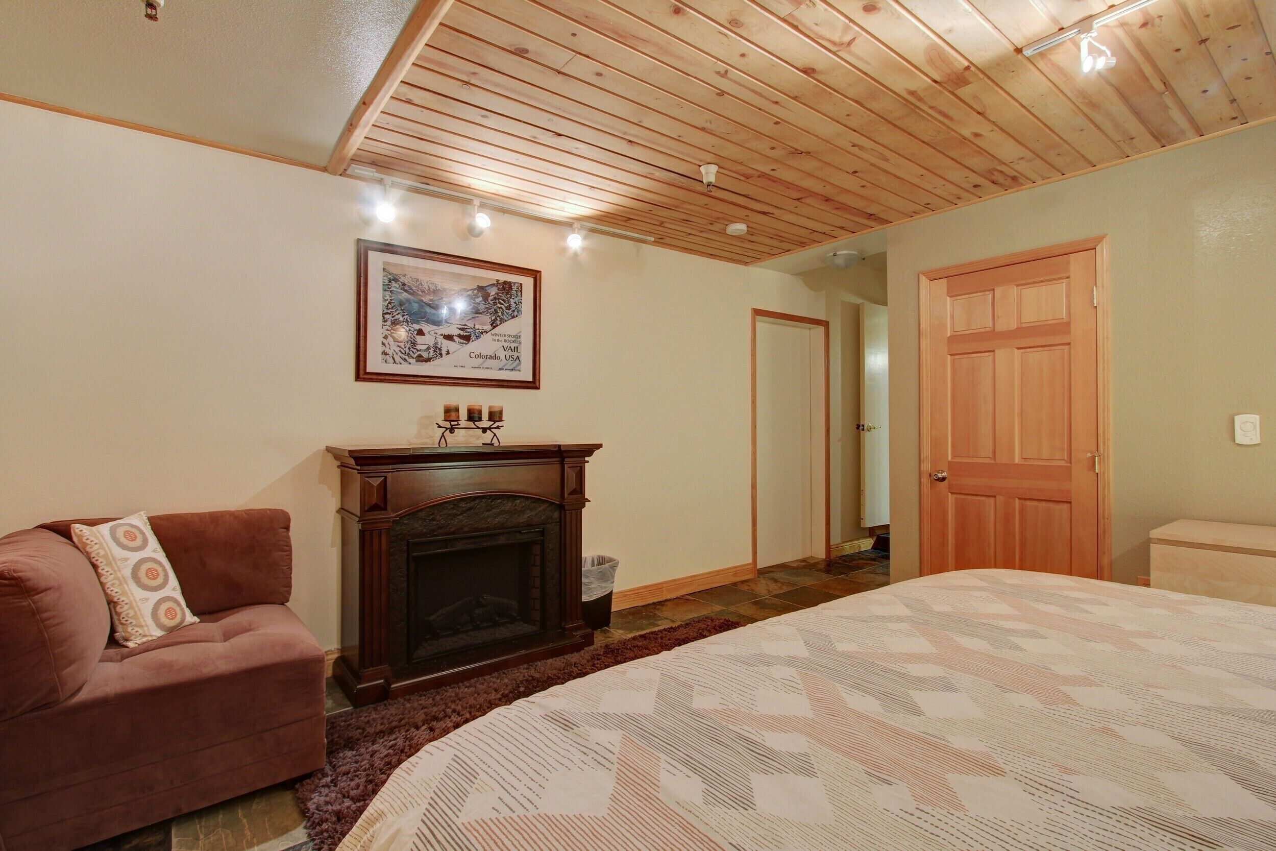Ein Schlafzimmer mit Kamin, einem Bett, einer Couch und einer Tür.