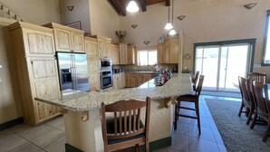 A kitchen with wooden cabinets, stainless steel appliances, a granite countertop, and a dining area with wooden chairs. - LABOR DAY WEEKEND IS NOW AVAILABLE - escape the heat! (Flagstaff)