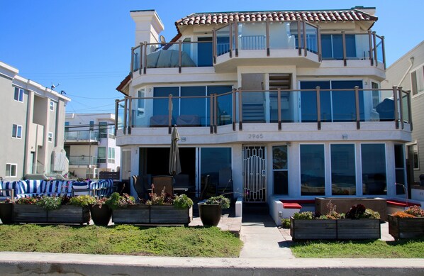 A multi-story residential building with balconies, large windows, and outdoor seating areas.