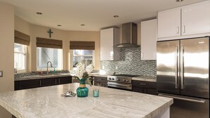 Una cocina moderna con una isla de mármol, electrodomésticos de acero inoxidable y un salpicadero de azulejos.