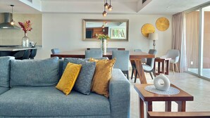 Una sala de estar moderna con un sofá gris, una mesa de centro de madera y un comedor con sillas y una mesa.