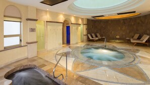 A spa area with a hot tub, lounge chairs, and a blue door. - Top Floor 2BR with ocean views in 5 star resort! (Cabo San Lucas)